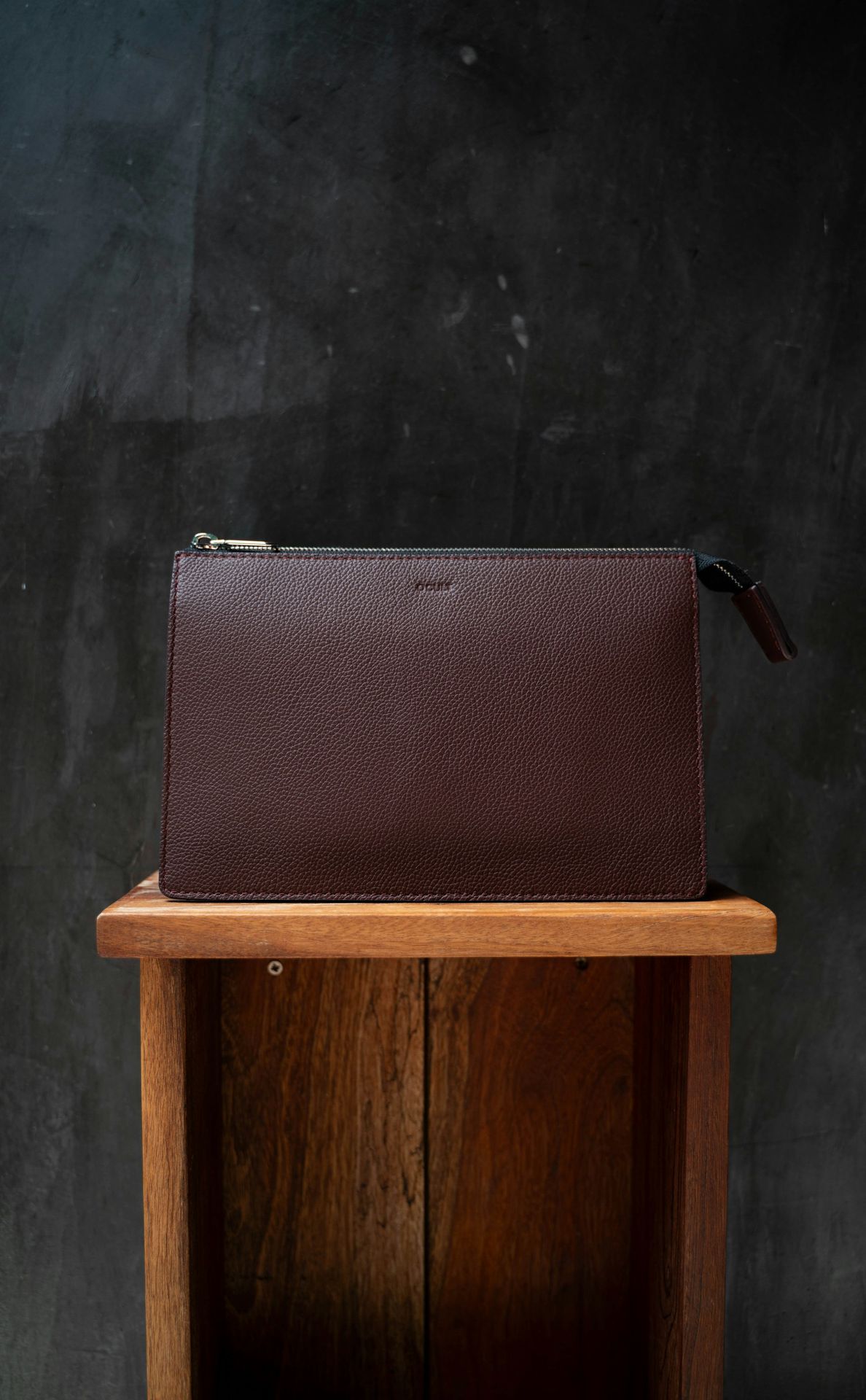 A brown clutch is on a wooden stand.